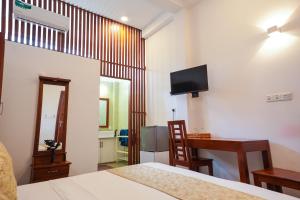 une chambre avec un lit, un bureau et une télévision dans l'établissement Grand Ranketha Resort, à Kalutara