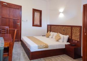 - une chambre avec un lit doté d'une tête de lit en bois et d'un bureau dans l'établissement Grand Ranketha Resort, à Kalutara