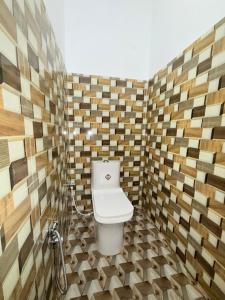a bathroom with a toilet in a room with wooden walls at Hotel embrace in Bhauli +5 photos