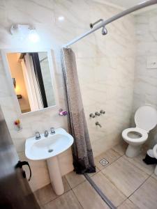 a bathroom with a sink and a toilet and a mirror at Departamentos Necochea Playa in Necochea