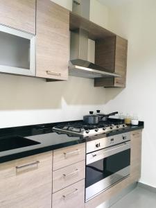 a kitchen with wooden cabinets and a stove top oven at Lucas Apart 2Bdr & 2Bth with pool in Mār Yūsuf