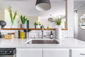 een witte keuken met een spoelbak en planten bij Jungle House Columbus Short North Downtown Free Parking - Steps to Convention Center & Nationwide Arena - 1BR Luxury Home - Sleeps 6 - Over 5,800 Five Star Stays in Columbus