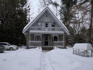 una piccola casa con neve per terra di Chalet Lumière a Rawdon