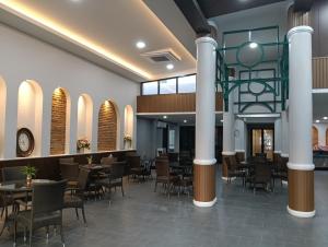 un ristorante con tavoli, sedie e colonne di KYP Hotel โรงแรมขุนยูวเพลส a Fang