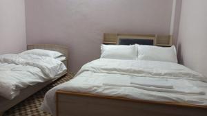 PokharaAnnapurna Himdrishya Pokhara的房间里有两张床，配有白色床单和枕头