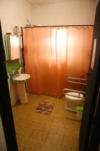een badkamer met een oranje douchegordijn en een toilet bij La Chakana Hostel Cultural in Ubatuba