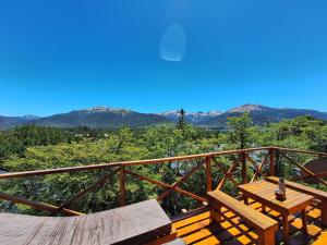 een houten balkon met een tafel en uitzicht op de bergen bij Parajes del lejano sur Cabaña El Patacón in Moquehue