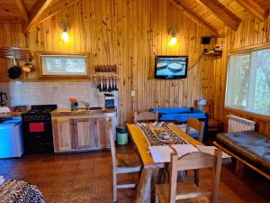 een keuken met een tafel in een houten kamer bij Parajes del lejano sur Cabaña El Patacón in Moquehue