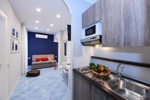 eine Küche mit einem Waschbecken und ein Wohnzimmer mit einem Sofa in der Unterkunft Appartamenti Amalfi Centro Storico in Amalfi + 13 Fotos