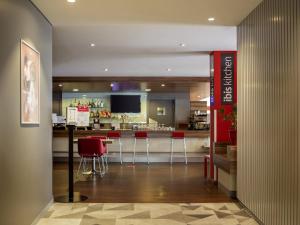 a restaurant with a bar with red chairs and a counter at Ibis Kaunas Centre in Kaunas