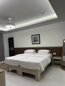 una camera con due letti e una parete bianca di Foavahi Shark View Inn a Fuvahmulah