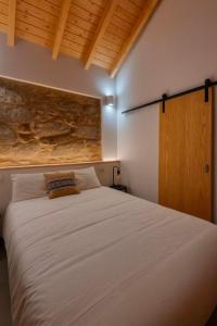 una camera da letto con un grande letto bianco e una porta in legno di Uíma River House 