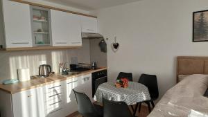 a kitchen with a table and chairs and a small kitchen with white cabinets at Kopaonik Alibi25 in Kopaonik
