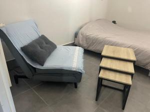a bedroom with a bed and a chair and a night stand at Petite Chambre avec SdB partagée in Angers