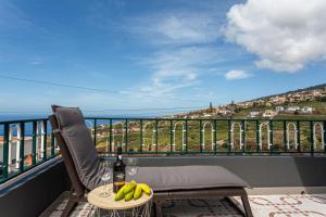 a table with a bottle of wine and bananas on a balcony at Estrela House I Calheta Madeira in Calheta