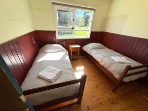 twee bedden in een kleine kamer met twee ramen bij Departamento tranquilo y equipado en parcela privada, cerca de comercios in Puerto Montt