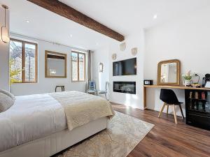 a white bedroom with a bed and a tv at Cottages Occitans in Villepinte