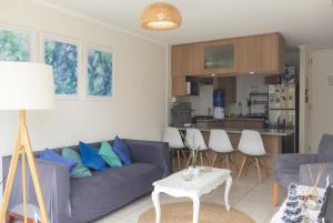 a living room with a blue couch and a kitchen at Departamento Sol in El Tabo