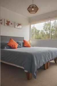 een slaapkamer met een groot bed met oranje kussens bij Departamento Sol in El Tabo +16 foto's