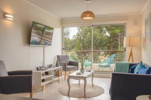 een woonkamer met stoelen en een tafel en een groot raam bij Departamento Sol in El Tabo