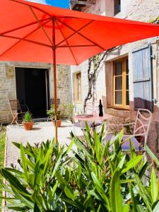 a table with a red umbrella in front of a building at Le Reve de Breuillac in Surin