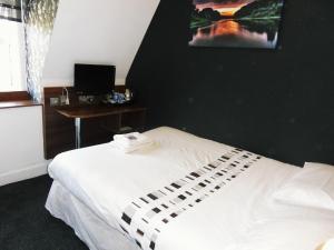 a white bed with a white comforter and pillows at Blossom Guest House in Edinburgh