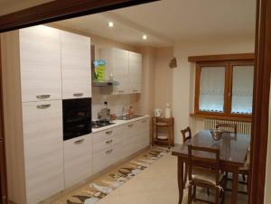 a kitchen with white cabinets and a wooden table at Casa Vacanze Giano in Antrodoco