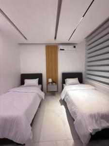 zwei Betten in einem Zimmer mit weißen Wänden in der Unterkunft Riva suites in Irbid
