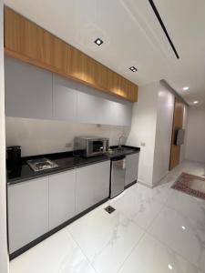 eine Küche mit weißen Schränken und einer Mikrowelle in der Unterkunft Riva suites in Irbid