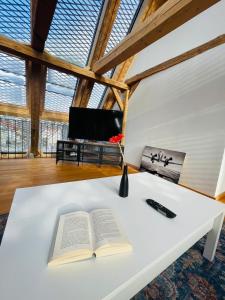 an open book on a white table with a tv at Schwarzwald Mauer Loft in Bräunlingen