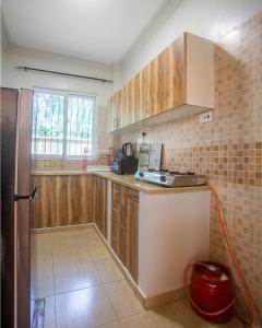 a kitchen with wooden cabinets and a red hose at SeyniKe 2BR Apartment - Nyali - AC, WiFi - Parking in Mombasa
