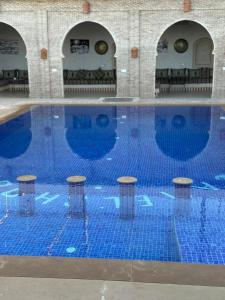 a large blue swimming pool with stools in it at Camels house apartment in Adrouine