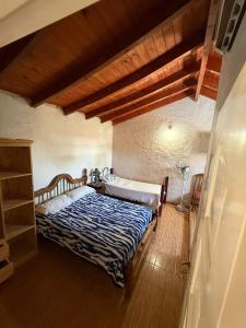 een slaapkamer met een bed en een houten vloer bij Hosteria las Palmeras in Mina Clavero