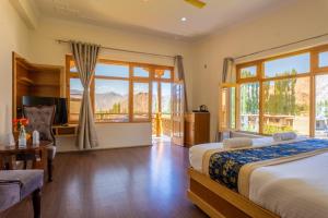 a bedroom with a bed and a desk and windows at The Nangsay Hotel in Leh +44 photos