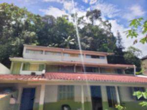 a green and white house with trees in the background at Quarto privado Brusque Centro ll in Brusque