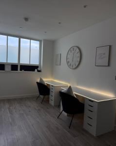 an office with two desks and a clock on the wall at Cosy flat that feels just like home in Leavesden Green