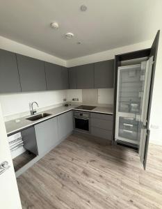 an empty kitchen with a sink and a refrigerator at Cosy flat that feels just like home in Leavesden Green
