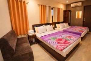 a hotel room with two beds and a chair at Hotel Sudarshan By Nath Bliss - Near Shrinathji Temple Just 2 Mins Walk in Nāthdwāra +7 photos
