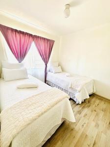 two beds in a bedroom with pink curtains at Small town comfort in Marquard
