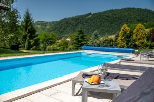 a swimming pool with a table with a bowl of fruit next to it at Private Pool Villa with Garden & Nature by Destination GREEN Croatia in Pregrada