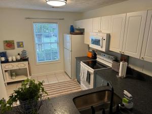 a kitchen with white cabinets and a sink and a microwave at Lovely 2BR 3BA Condo in Auburn
