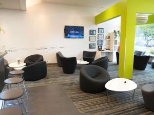 een wachtkamer met zwarte stoelen en tafels bij ibis Styles Caen centre gare in Caen