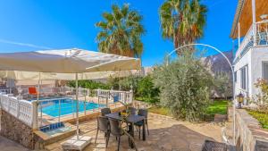 a patio with a table and an umbrella next to a pool at Villa Neymar in Kaş