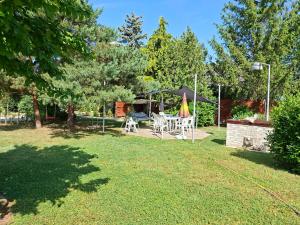 un cortile con tavolo, sedie e ombrellone di SUNFISH Apartman a Balatonszárszó