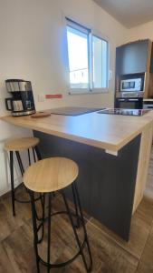 a kitchen with a counter and two bar stools at Maison proche Futuroscope in Chasseneuil-du-Poitou