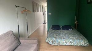 a bed in a room with a couch and a green wall at Le Cosy in Chalon-sur-Saône