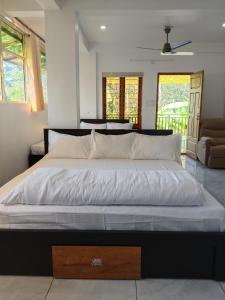 a bedroom with a large bed with white sheets at V Land Homestay in Vagamon