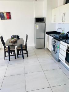 een keuken met een tafel, een fornuis en een vaatwasser bij Kingelph Stylish 1- Bedroom Apartment in Windhoek