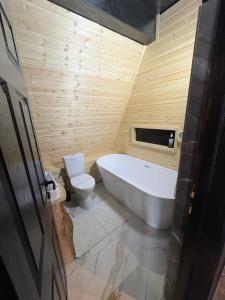 un bagno con una vasca bianca e un water di Black Chalet 2 a Vârtop Altre 5 foto