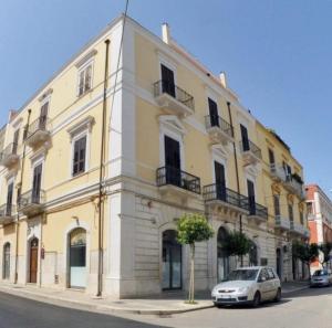 een geel gebouw met een auto ervoor geparkeerd bij Tiare' in Trani